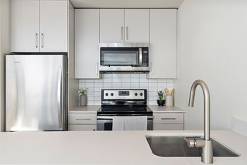A modern kitchen with a stainless steel refrigerator, microwave, and oven.